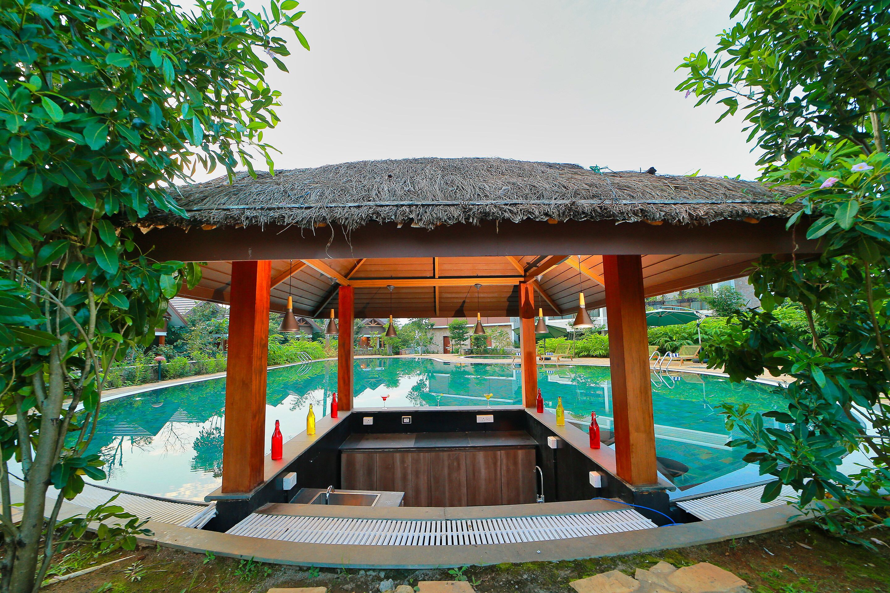 A covered hot tub area with a pool in the background.