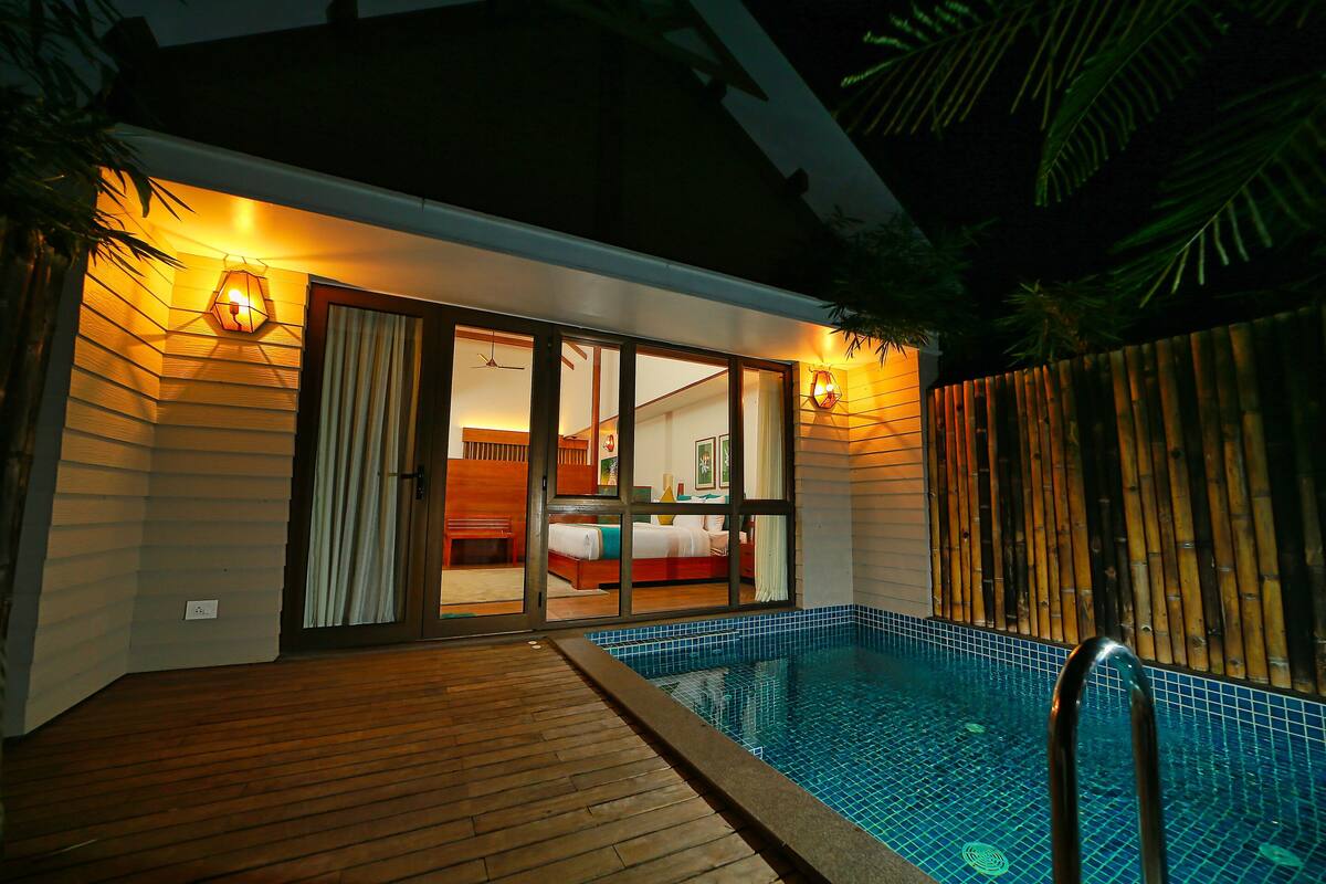 Une chambre d’hôtel avec piscine, une terrasse en bois et des portes coulissantes en verre donnant sur la chambre.