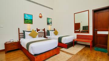 A hotel room with two beds, wooden headboards, a bench, and artwork on the walls.