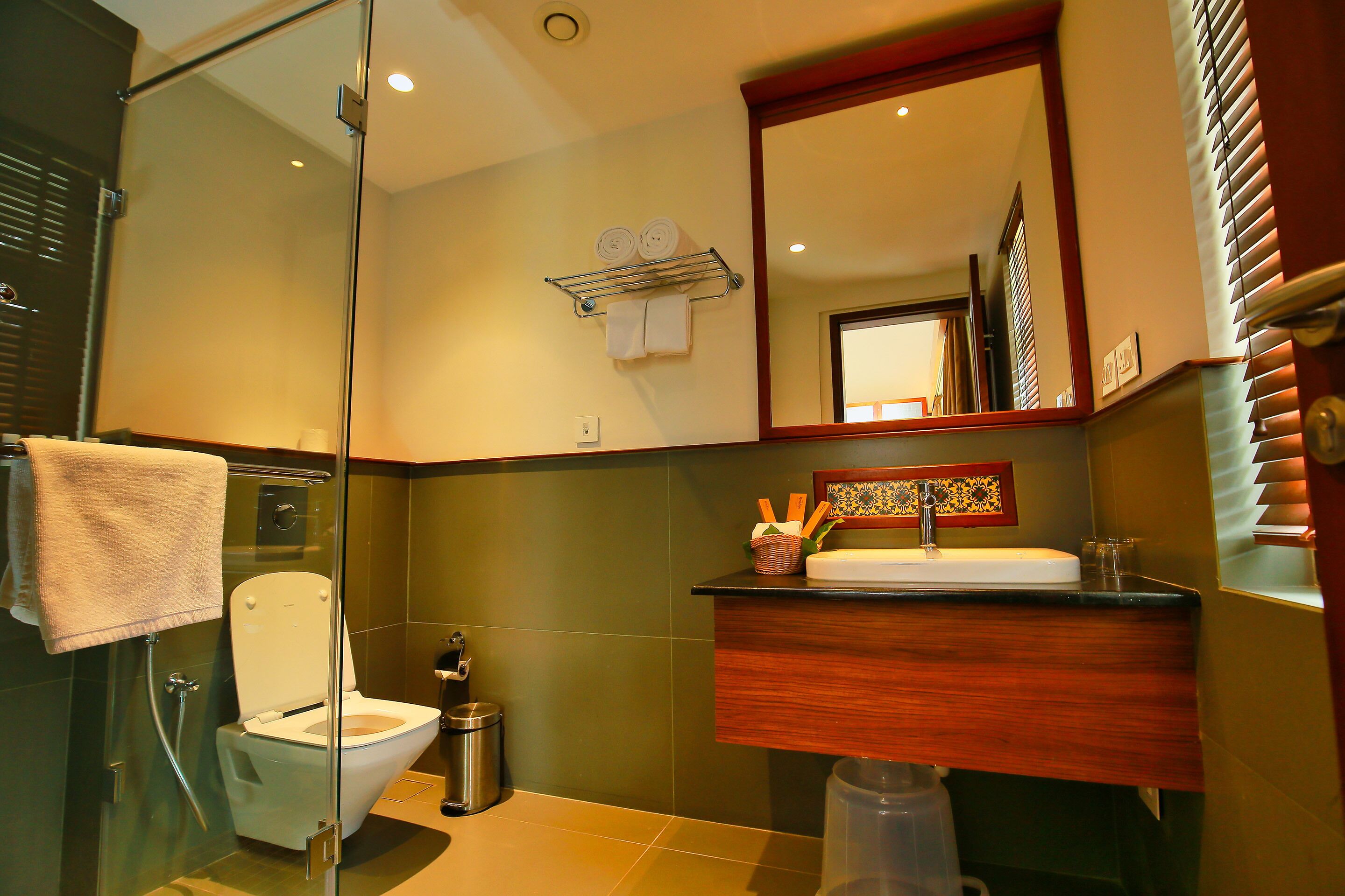 A bathroom with a glass-enclosed shower, a white toilet, a sink with a wooden countertop, and a mirror above the sink.
