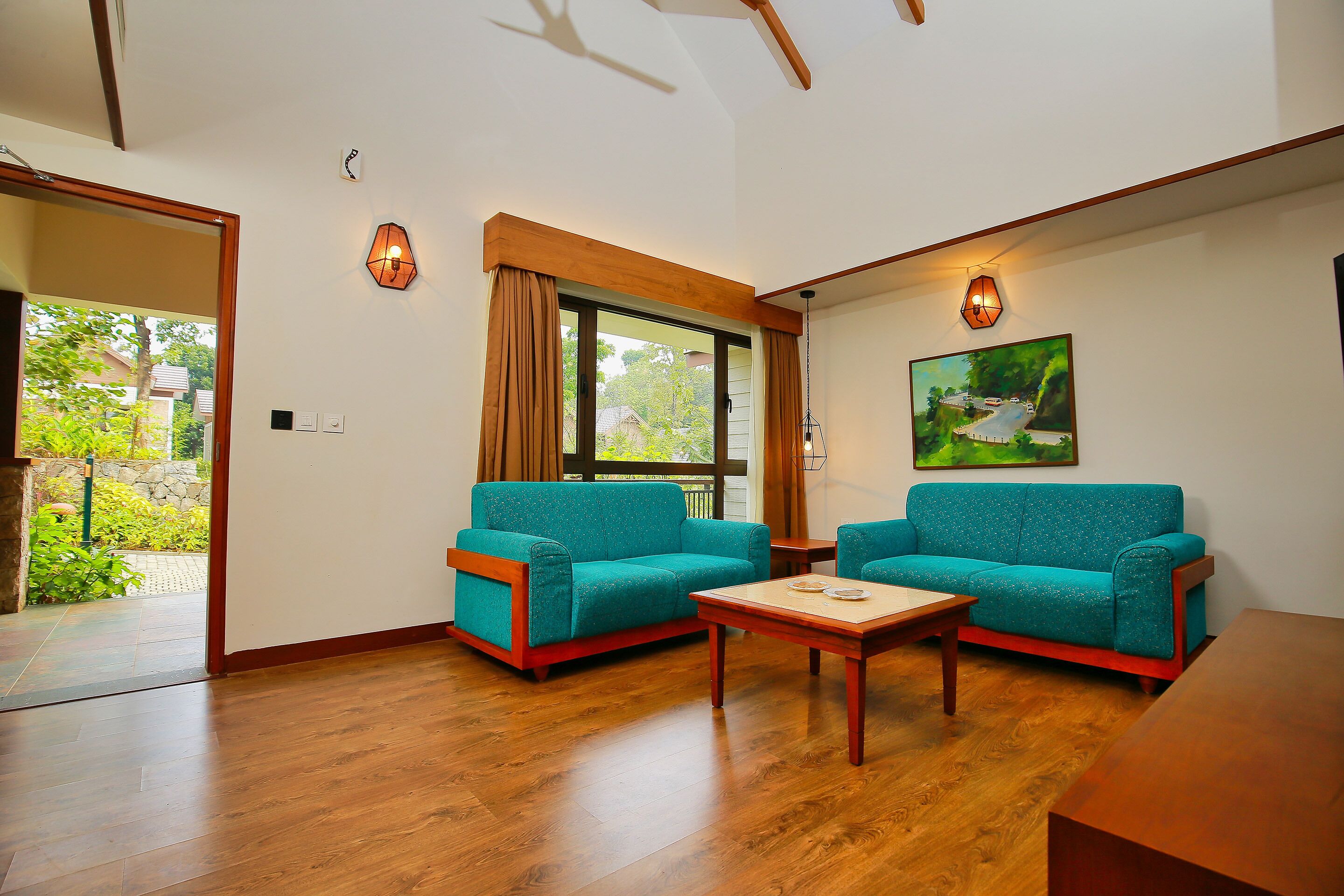Una sala de estar con dos sofás color turquesa, una mesa de centro de madera y un cuadro en la pared.