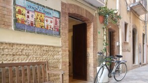 Un banco de piedra frente a un edificio con un mural de azulejos y una bicicleta estacionada cerca.