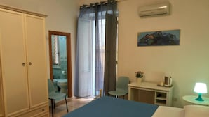 Un dormitorio con cama, escritorio, silla, armario y aire acondicionado.