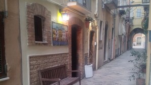 Un callejón estrecho con un banco, una planta en maceta y un mural en la pared.