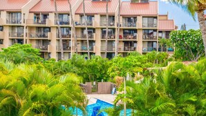 A multi-story hotel with balconies, a swimming pool, and lush tropical vegetation.