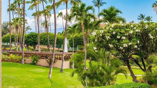 A lush garden with tall palm trees and a clear blue sky.