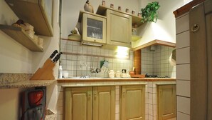 Eine Küche mit Holzausstattung, einem Spülbecken, einem Herd und einer Arbeitsplatte mit verschiedenen Küchenutensilien.