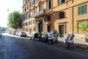 A cobblestone street lined with parked cars and motorcycles. - Charming Flat close to Colosseum (roma)