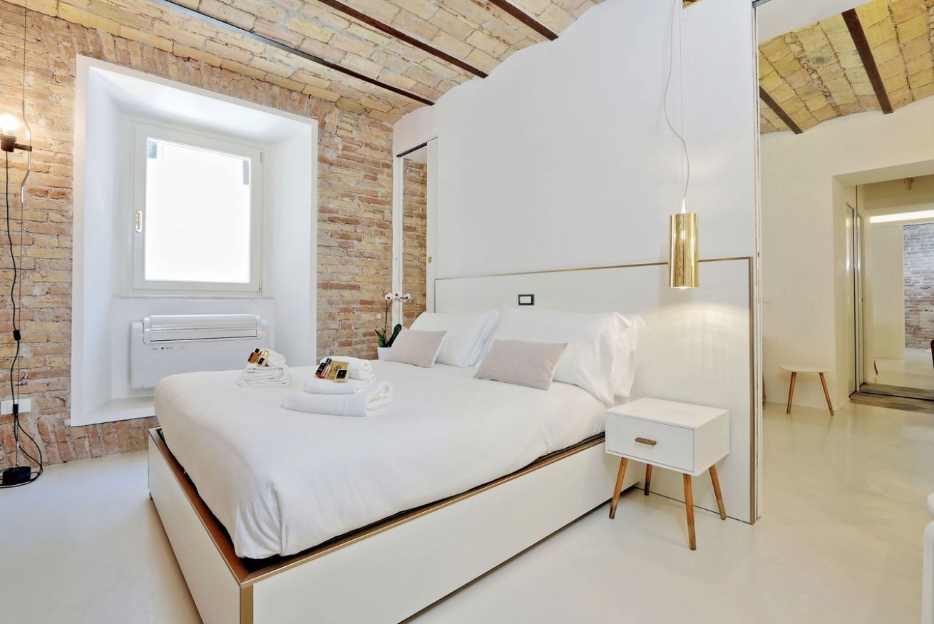 Een moderne slaapkamer met een groot bed, een nachtkastje, een wandheater en een raam met uitzicht.