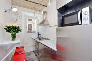 Una cucina moderna con frigorifero in acciaio inossidabile, forno a microonde e piano cottura a gas.