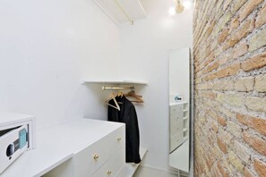 Un bagno moderno con un mobile lavabo bianco, un appendi-asciugamani a parete e una parete in mattoni.