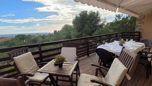 Eine Holzdielen-Terrasse mit Esstisch und Stühlen, mit Blick auf eine schöne Landschaft.
