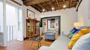 Un soggiorno con soffitto in legno, un divano grigio, un tavolino e un mobiletto con ante in vetro.