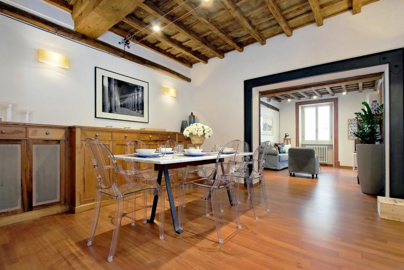 A dining area with a wooden ceiling, clear chairs, and a table set for four.
