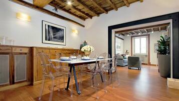 A dining area with a wooden ceiling, clear chairs, and a table set for four.