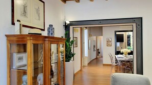 Un'ampia hall con pavimento in legno, una vetrina con sculture e opere d'arte incorniciate alle pareti.