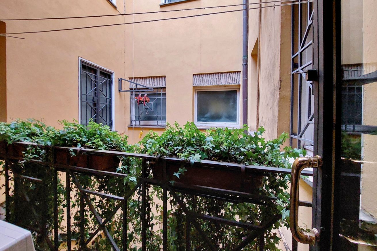 Un balcon avec une balustrade en métal, une fenêtre avec une grille en métal et une porte avec une poignée en laiton.