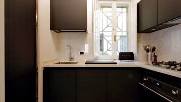 A modern kitchen with dark cabinetry, a built-in oven, and a window providing natural light.