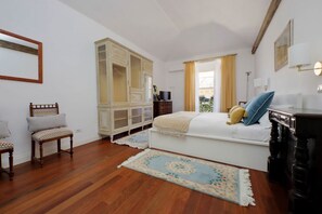 Ein Schlafzimmer mit einem Bett, einem Kleiderschrank, einem Spiegel, einem Schreibtisch und einem Stuhl.