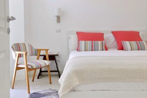 A bedroom with a bed, a chair, a nightstand, and a lamp.