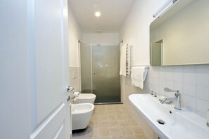 Un baño moderno con ducha, inodoro, bidé y una bañera grande.