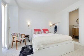 Un dormitorio con cama, una silla, un armario y un espejo.