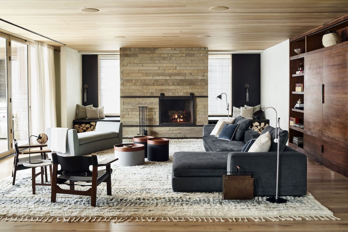 A modern living room with a fireplace, a sofa, a coffee table, and a bookshelf.