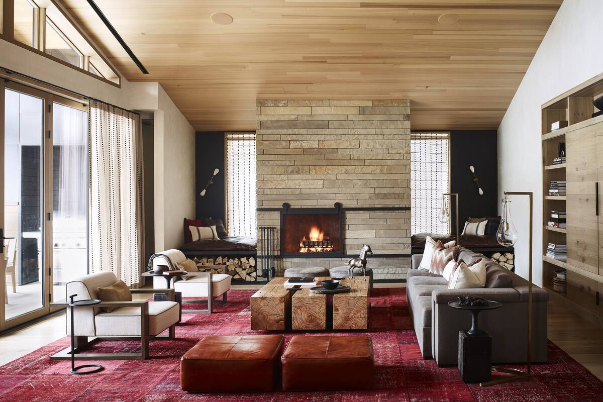 A spacious living room with a large fireplace, wooden ceiling, and a red carpet.