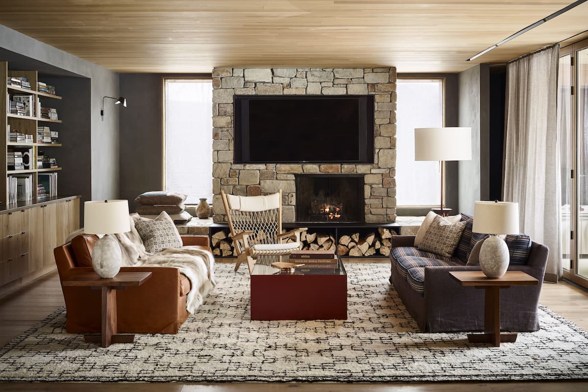 A modern living room with a stone fireplace, comfortable seating, and a large flat-screen TV.