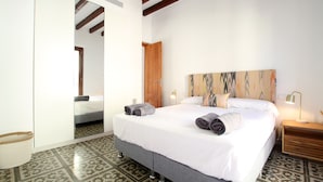 A neatly made bed with rolled towels, a wooden nightstand with a lamp, and a patterned floor. - Pius Eleven by Balearic Villas (Pollensa)