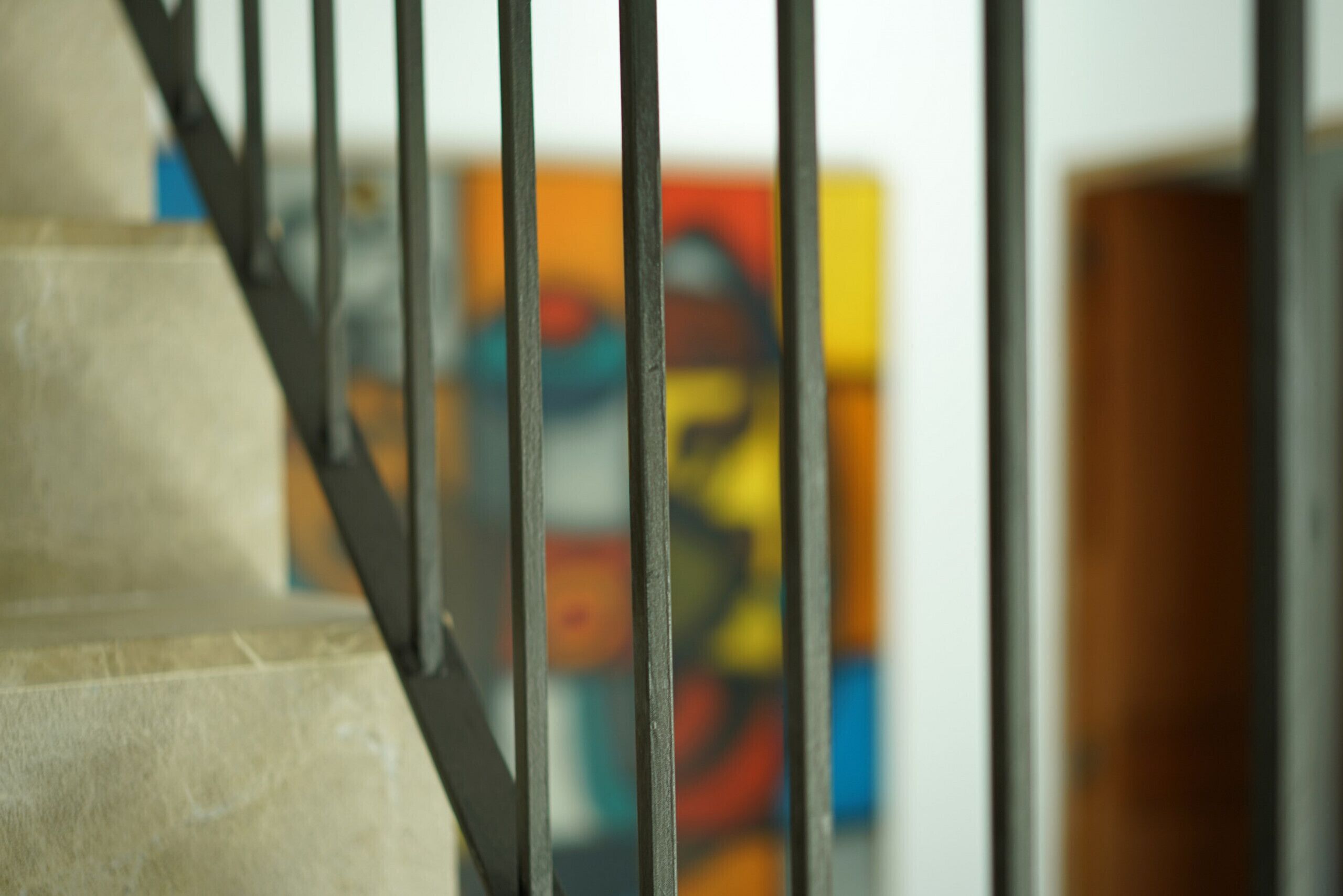 A staircase with metal railings and a blurred background featuring colorful artwork.