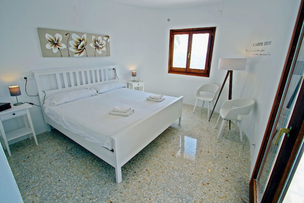 A bedroom with a bed, bedside tables, a chair, a window, and a wall decoration.