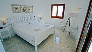 A bedroom with a bed, bedside tables, a chair, a window, and a wall decoration. - Suerte - sea view villa with private pool in Moraira (Moraira)