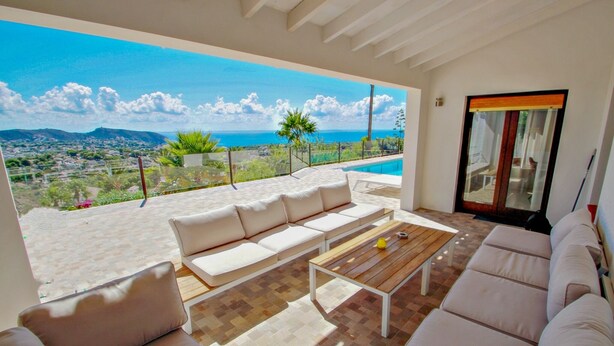 A spacious outdoor seating area with a sofa and a coffee table, overlooking a scenic view of the ocean and mountains. - Suerte - sea view villa with private pool in Moraira (Moraira)