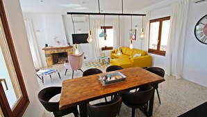 A dining area with a wooden table and chairs, a yellow sofa, and a fireplace in the background. - Suerte - sea view villa with private pool in Moraira (Moraira)