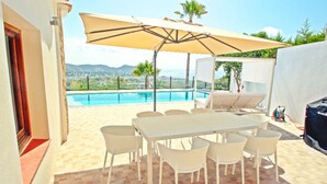 An outdoor patio with a pool, a table with chairs, and a large umbrella. - Suerte - sea view villa with private pool in Moraira (Moraira)