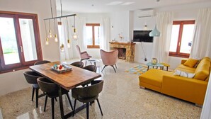 A modern living room with a wooden dining table, chairs, a yellow sofa, and a fireplace. - Suerte - sea view villa with private pool in Moraira (Moraira)