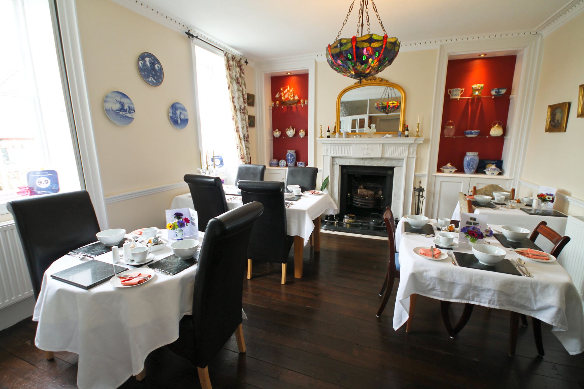 A dining area with multiple tables set for service, a fireplace, and a chandelier.