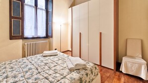 Une chambre à coucher avec un lit, une fenêtre, un radiateur, une armoire et une chaise.