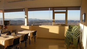A conference room with a view of distant mountains, a table with a laptop, and a stack of green chairs. - Hotel SG Bullas (Bullas)