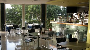 A modern restaurant with a bar area, large windows, and a view of trees. - Hotel SG Bullas (Bullas)