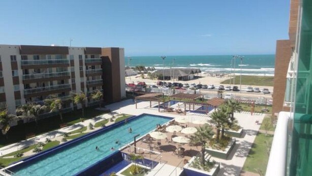 Un hotel con zona de piscina, vistas a la playa y aparcamiento.