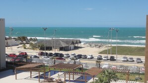 Un hotel frente a la playa con piscina, sombrillas y vistas al océano.