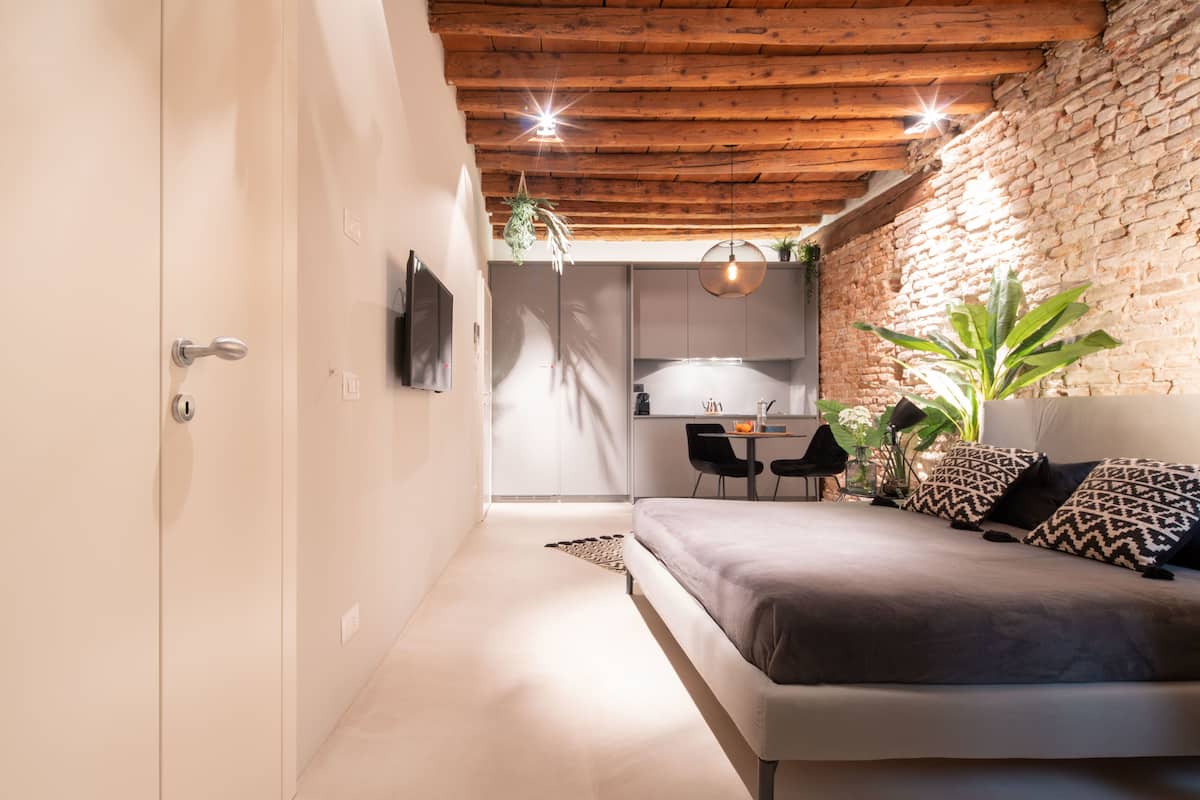 A modern bedroom with a wooden ceiling, a sofa, a TV, and a dining area with chairs and a table.