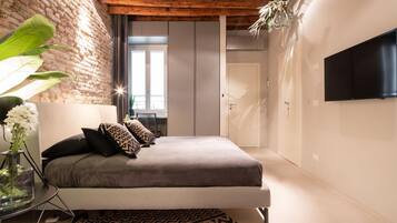 Une chambre avec un lit, une télévision, une plante et un mur en briques.