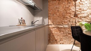 A modern kitchen with a brick wall, stainless steel appliances, and a black chair. - Officine Cavour Apartments (Padova)