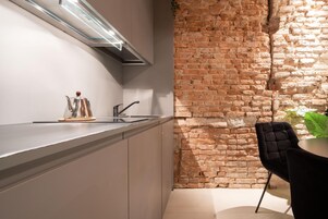 Uma cozinha moderna com parede de tijolos, eletrodomésticos de aço inoxidável e uma cadeira preta.