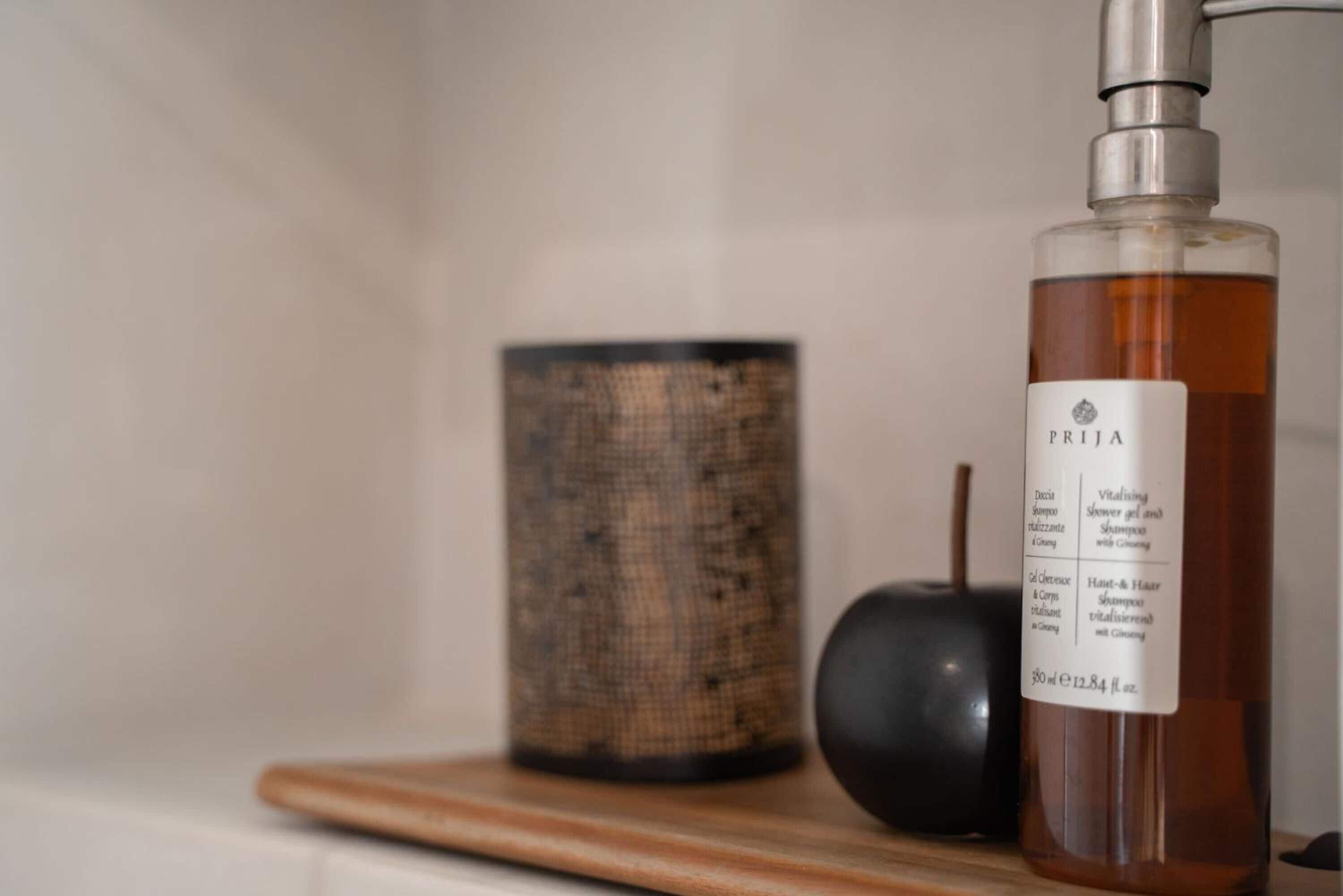 A bottle of PRIZA shower gel on a wooden surface with a textured container and a black object in the background.