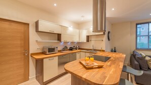 A modern kitchen with a wooden countertop, built-in appliances, and a breakfast setup. - Hampden Apartments - The Catherine (Windsor)