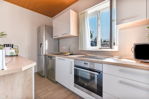 Eine moderne Küche mit Edelstahlgeräten, einer Holzarbeitsplatte und einem Fenster mit Blick.